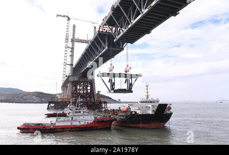 (190925) - FUZHOU, Sept. 25, 2019 (Xinhua) - Foto auf Sept. 21, 2019 zeigt einen stahlträger von einem Kran auf der Baustelle des Pingtan Meerenge Straße - Schiene Brücke im Südosten der chinesischen Provinz Fujian. China am Mittwoch abgeschlossen Die Struktur der längsten der Welt - Sea Road - Eisenbahnbrücke in Fujian. Die letzte Stahlträger, mit einem Gewicht von 473 Tonnen, war auf der Pingtan Meerenge Straße verschraubt - Rail Bridge, ein mega Projekt in China, am Mittwoch Morgen. Mit einer Spannweite von 16.34 m, die Brücke verbindet Pingtan Insel und vier nahe gelegenen Inseln mit dem Festland von Stockfoto