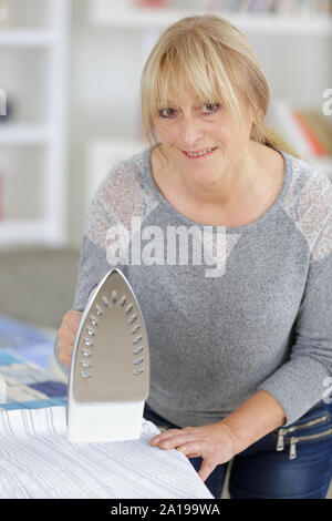 Freundliche asiatische reife Frau bügeln Hemden Stockfoto