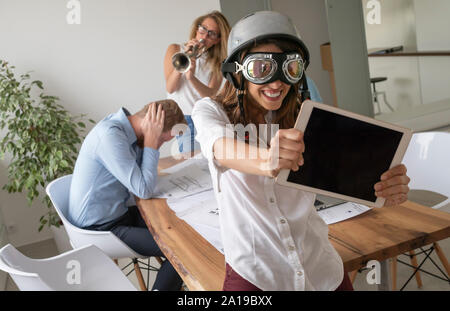 Freunde spielen einen Streich, ihre Kollegen im Büro. Schlechte Arbeitsbedingungen Stockfoto