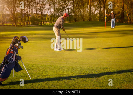 Zwei ältere Golfspieler Golf spielen in der Abenddämmerung. Stockfoto