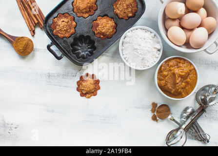 Schöne frische hausgemachte Kürbis Muffins mit kürbispüree, Mehl, Zimt und braune Eier über hellen Hintergrund. Bild geschossen von der Ansicht von oben. Stockfoto