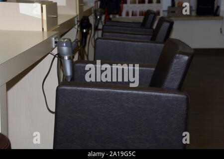 Leere Beauty Salon mit Sesseln und Haartrockner, Innenraum eines modernen Friseursalon mit Sesseln in einer Reihe Stockfoto