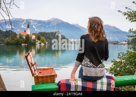 Junge Frau auf der Bank sitzen enjoining die Ansicht vom See Bled Stockfoto
