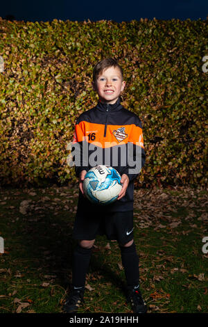 Ein acht Jahre alter Junge trägt eine Fußball-Streifen und halten einen Fußball in den Händen. Stockfoto