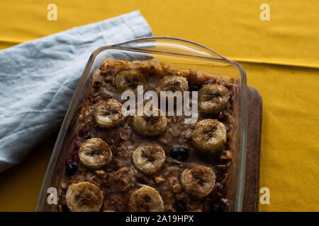 Gebackene Haferflocken mit Bananen, Blaubeeren, und Walnüsse. in einer Glasschale serviert. Stockfoto
