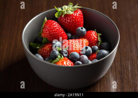 Ansicht von oben Nahaufnahme von frischen roten Beeren, Erdbeeren und Heidelbeeren in eine Schüssel geben. Stockfoto