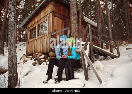 Mann und Frau sitzen auf der Veranda eines Hauses. junge glückliche Paar in Liebe im Freien im winter Stockfoto