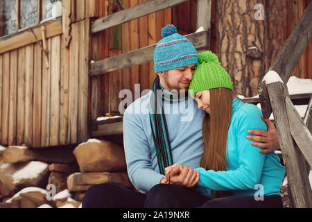 Mann und Frau sitzen auf der Veranda eines Hauses. junge glückliche Paar in Liebe im Freien im winter Stockfoto
