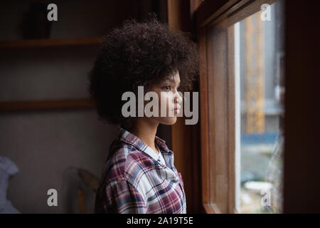 Junge Frau aus dem Fenster schauen Stockfoto