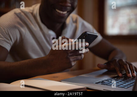 Junger Mann mit Smartphone und Laptop Stockfoto