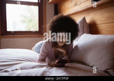 Junge Frau mit Smartphone im Bett Stockfoto