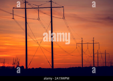 Hohe Spannung der Drähte an den Sonnenuntergang. Eine lange Linie der elektrischen Kabel Stockfoto