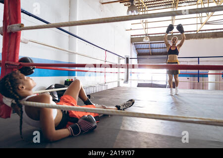 Weibliche boxer Feiern nach unten klopfen, ihren Gegner im Boxring Stockfoto
