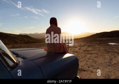 Junge Frau sitzt auf einem Pick-up-Truck bei einem Zwischenstopp auf einer Reise Stockfoto