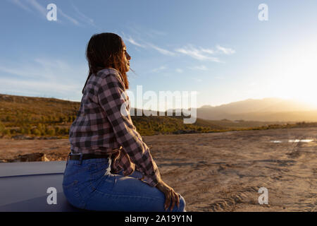 Junge Frau sitzt auf einem Pick-up-Truck bei einem Zwischenstopp auf einer Reise Stockfoto