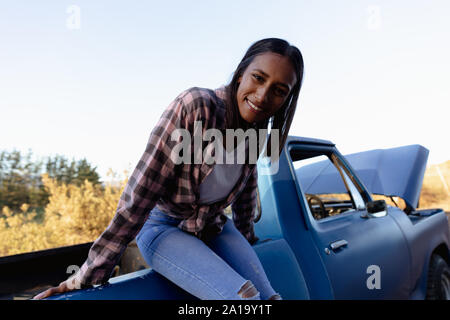 Junge Frau sitzt auf einem Lkw am Straßenrand Stockfoto