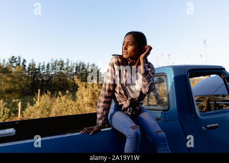 Junge Frau sitzt auf einem Lkw am Straßenrand Stockfoto