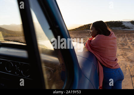 Junge Frau lehnte sich auf einen Pick-up-Truck bei einem Zwischenstopp auf einer Reise Stockfoto