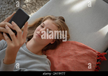 Junge blonde Frau liegend mit Smartphone Stockfoto