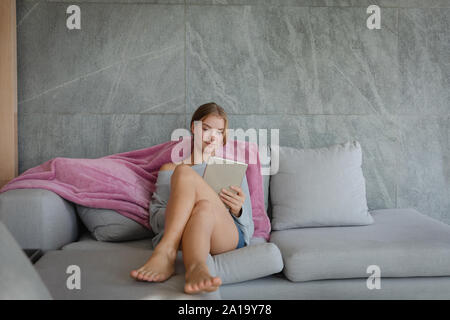 Junge blonde Frau in einem Apartment mit Tablet Stockfoto