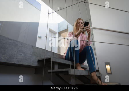 Blonde Junge sitzt auf Treppe Frau mit Smartphone Stockfoto