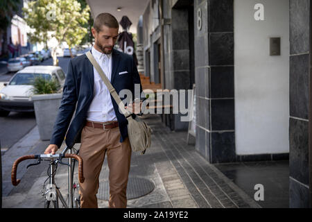 Young Professional Mann mit Smartphone und halten ein Fahrrad Stockfoto