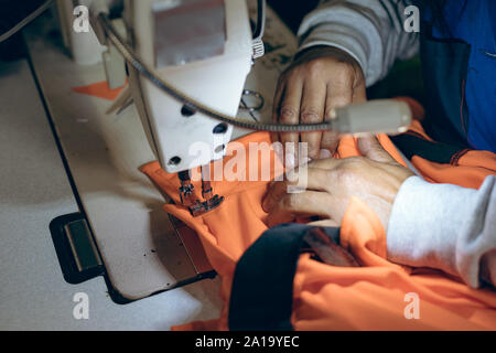 Die Hände einer Frau mit einer Nähmaschine in einer Fabrik Stockfoto