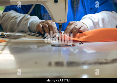 Die Hände einer Frau mit einer Nähmaschine in einer Fabrik Stockfoto