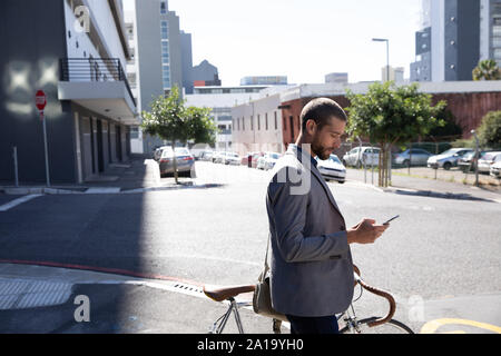 Young Professional Mann mit Smartphone und halten ein Fahrrad Stockfoto