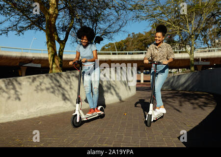 Zwei junge Frauen reiten e Scooter Stockfoto