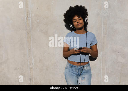 Junge Frau anhören von Musik im freien Stockfoto