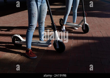 Zwei junge Frauen reiten e Scooter Stockfoto