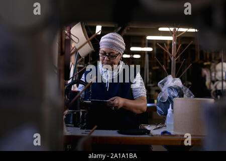Frau mit Nähmaschine in einer Hutfabrik Stockfoto