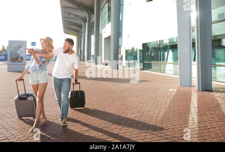 Glückliches Paar am Flughafen ankommen, ziehen die Koffer im Freien Stockfoto