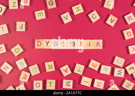 Holz- alphabet Blöcke mit Legasthenie Wort in der Mitte auf rosa Hintergrund. Konzept der Legasthenie das Bewusstsein und die Entwicklung des Gehirns Stockfoto