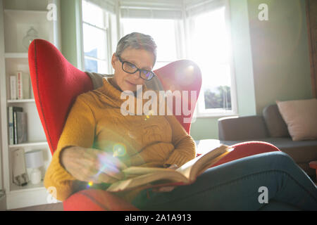 Reife Frau alleine zu Hause lesen Buch Stockfoto
