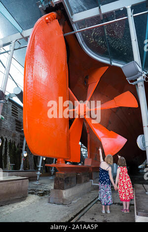 Kind Gast touristische Kinder geben zu Schraube Isambard Kingdom Brunel's Propeller, Ruder- und Schiffskörper der SS Great Britain, unter der gläsernen Meer im Trockendock, Dockyard Museum in Bristol. Großbritannien (109) Stockfoto