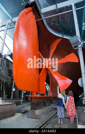 Kind Gast touristische Kinder geben zu Schraube Isambard Kingdom Brunel's Propeller, Ruder- und Schiffskörper der SS Great Britain, unter der gläsernen Meer im Trockendock, Dockyard Museum in Bristol. Großbritannien (109) Stockfoto