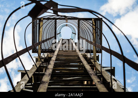 Alte rostige Treppe mit Schadensersatz gegen den blauen Himmel und Wolken Stockfoto