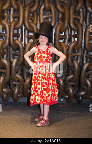 Girl/Kind/Kinder/kid tragen Top Hat und vor der großen Ketten stellen das berühmte Foto von Isambard Kingdom Brunel, die von Robert Howlett zu emulieren. Auf der begleitenden Ausstellung werden Brunel SS Great Britain Schiff, Werft, Bristol England UK (109) Stockfoto