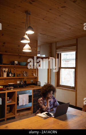 Junge Frau mit Laptop in einer Küche Stockfoto