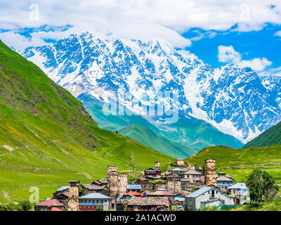 Wunderbare Aussicht auf Dorf in den Bergen gegen den blauen Himmel in der Region Swanetien, Georgia. Traditionelle alte Svan Türme auf einem grünen Hügel an einem sonnigen Tag Stockfoto
