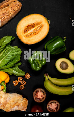 Verschiedene Gemüse und Baguette auf schwarzem Hintergrund. Vegan gesundes Essen Stockfoto