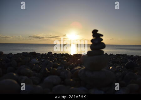 Haufen von Steinen am Strand vor Sonnenuntergang Stockfoto