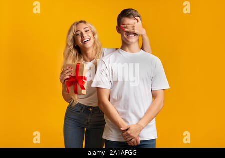 Mädchen die Augen ihres Freundes und Ihm vorhanden Stockfoto