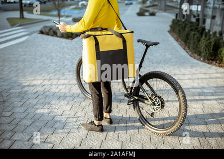 Kurier Lieferung von Nahrung in einem gelben thermo Tasche mit einem Fahrrad in der Stadt, in der Nähe auf dem Beutel mit Kopie Raum konzentriert Stockfoto