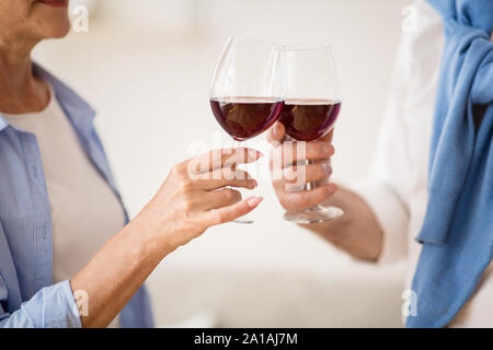 Reifes Paar klirren Gläser mit Rotwein zu Hause Stockfoto