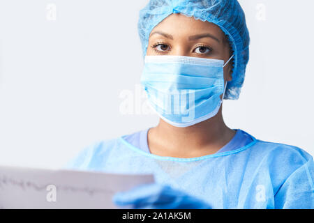 Studio Portrait von weiblichen Chirurg tragen Kleid und Maske Holding medizinischen Ausdrucken Stockfoto