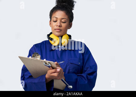 Studio Shot der Ingenieurin mit Klemmbrett und Schraubenschlüssel gegen den weißen Hintergrund Stockfoto