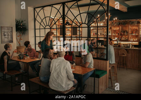 Diverse Freunde Bestellung von Getränken von der Bar Kellnerin bei Nacht Stockfoto